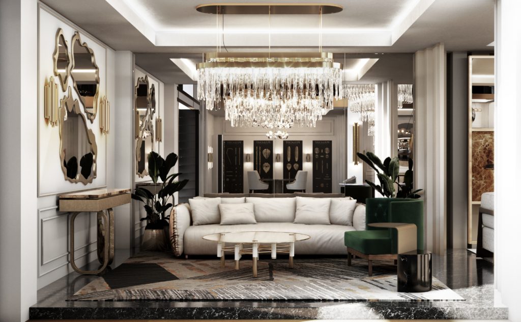 Cannes - living area with a chandelier, a grey sofa with golden details, a set of three mirrors, a green armchair and a round center table